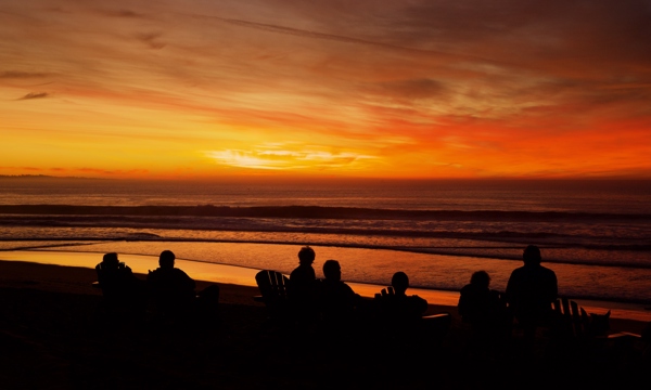 Guests looking out over a fiery sunset from the Sanctuary beach resort in Marina, California